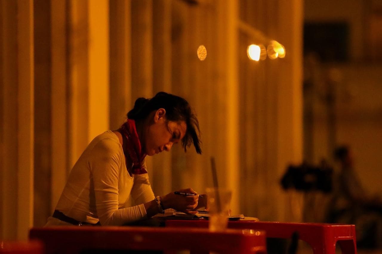 Kathy Uyen writing at a table, late at night