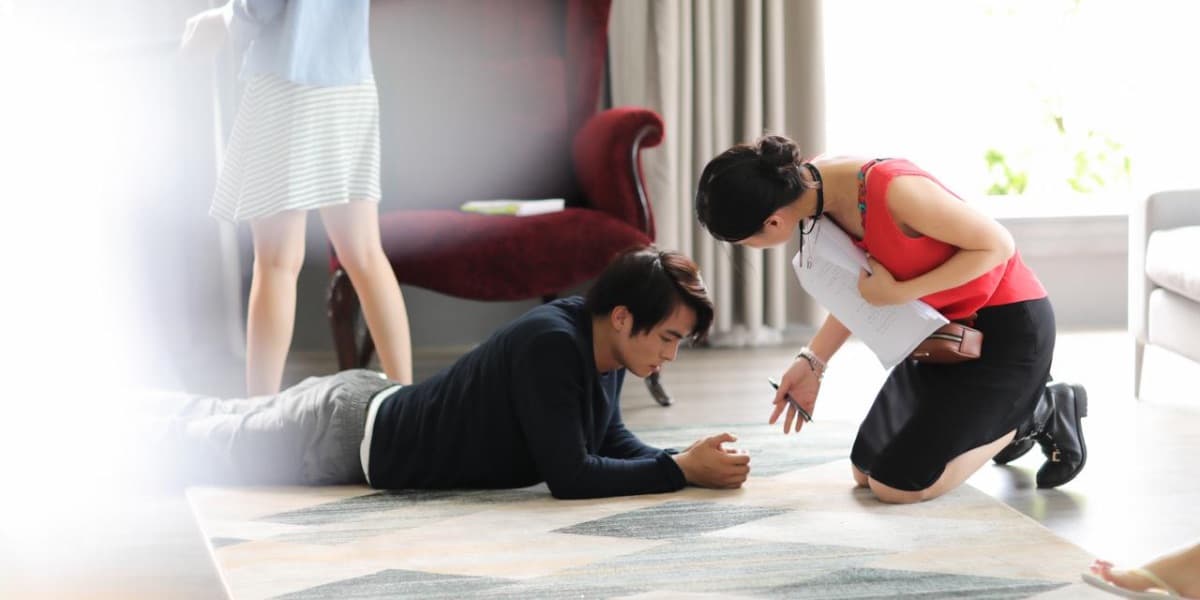 Kathy Uyen kneeling beside an actor, directing a scene on set