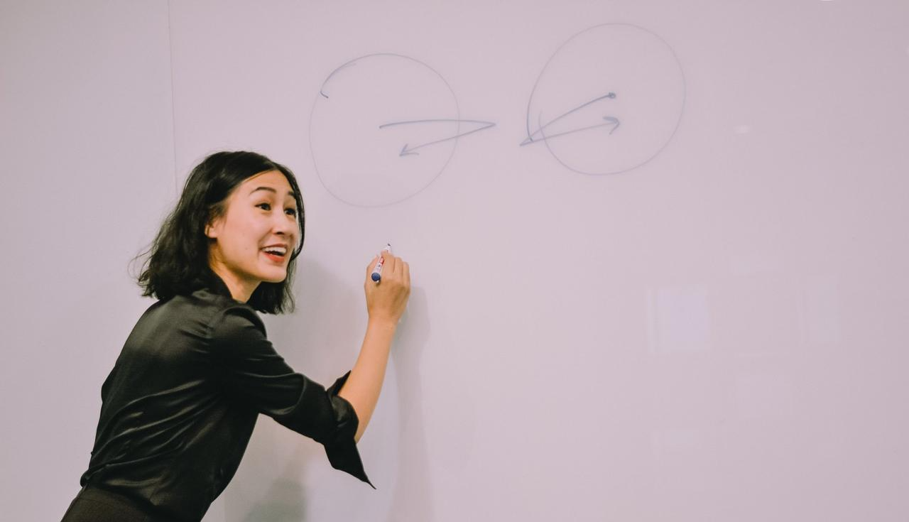 Kathy Uyen at a whiteboard, mid-teaching